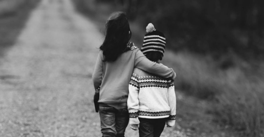 boy and girl walking down the road in black and white