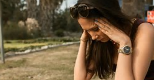 Crouching woman stressed out with hands on head looking down