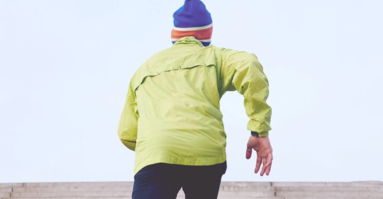 A person runs up the bleacher in running outfit that is yellow and blue 